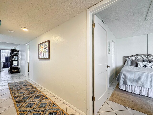 corridor featuring tile patterned flooring and a textured ceiling