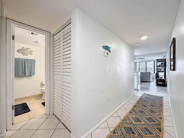 hall featuring light tile patterned floors and a textured ceiling