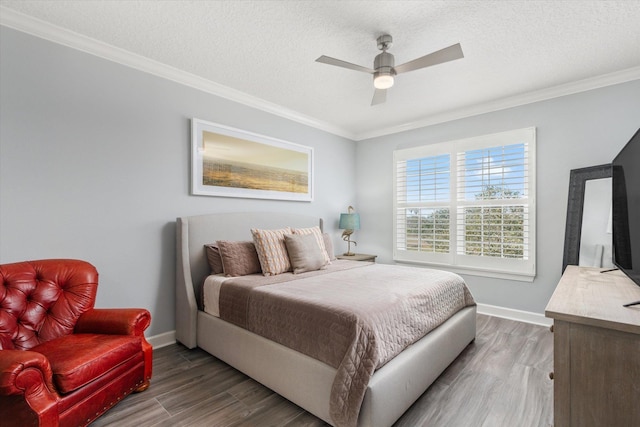 bedroom with a textured ceiling, ornamental molding, wood finished floors, and baseboards