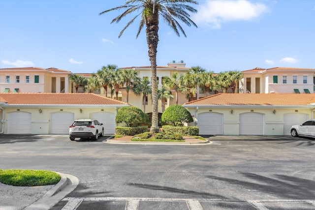 view of front of home featuring a tiled roof, community garages, and stucco siding