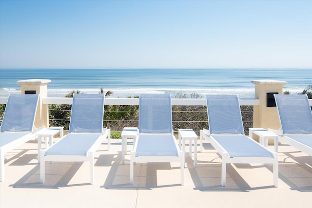 view of patio featuring a water view and a beach view