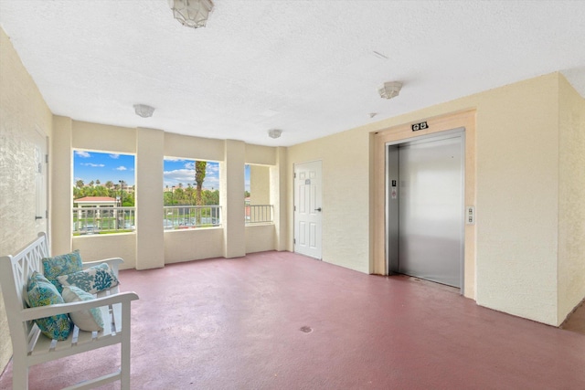 interior space featuring a textured ceiling and elevator