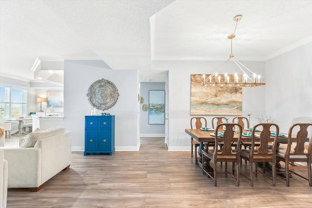 dining room featuring crown molding, a notable chandelier, a textured ceiling, and wood finished floors