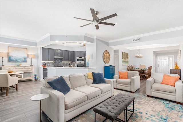 living area with light wood-style floors, a textured ceiling, visible vents, and crown molding