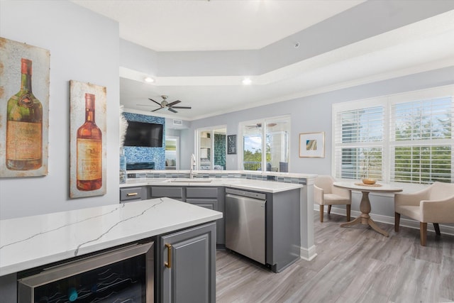 kitchen with gray cabinetry, beverage cooler, a fireplace, a sink, and dishwasher