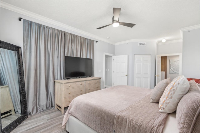 bedroom featuring light wood-type flooring, visible vents, ornamental molding, and a textured ceiling