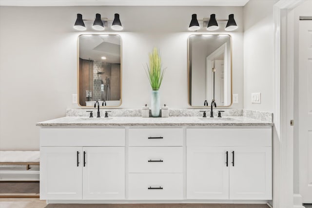 bathroom with double vanity, a shower with door, and a sink