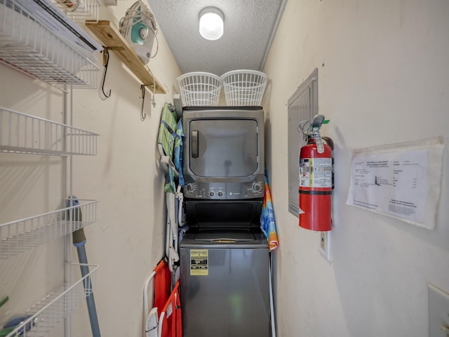 clothes washing area featuring a textured ceiling and stacked washer and clothes dryer