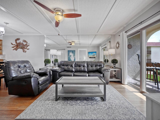 living room with hardwood / wood-style flooring, ceiling fan, and a textured ceiling