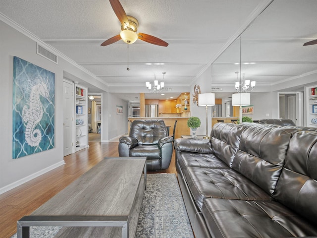 living room featuring hardwood / wood-style floors, ceiling fan with notable chandelier, a textured ceiling, and ornamental molding