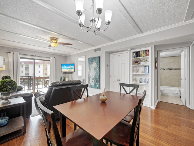 dining space featuring ceiling fan with notable chandelier, hardwood / wood-style floors, a textured ceiling, and built in features