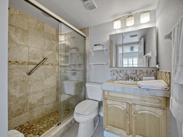 bathroom with tasteful backsplash, vanity, a shower with door, tile patterned flooring, and toilet