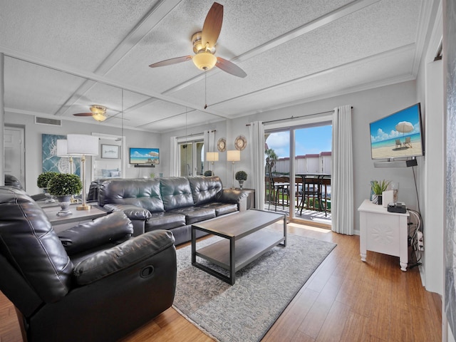 living room with a textured ceiling, light hardwood / wood-style floors, ceiling fan, and crown molding