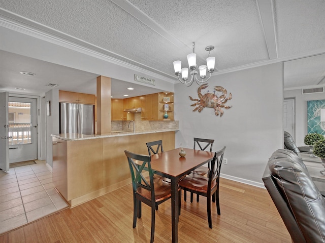 dining area with crown molding, light hardwood / wood-style flooring, a textured ceiling, and an inviting chandelier