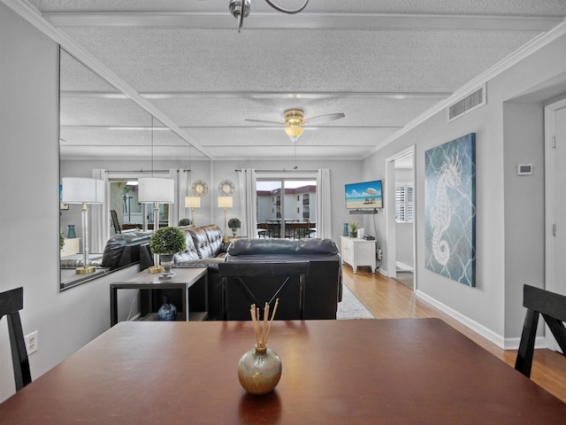 dining space featuring ceiling fan, hardwood / wood-style floors, crown molding, and a textured ceiling