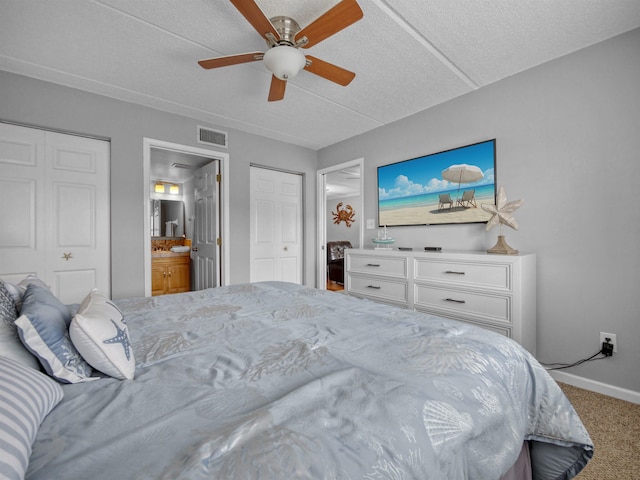 bedroom featuring ensuite bath, ceiling fan, a textured ceiling, carpet floors, and multiple closets