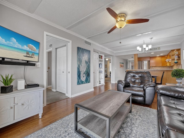 living room with hardwood / wood-style flooring, ceiling fan with notable chandelier, ornamental molding, and a textured ceiling