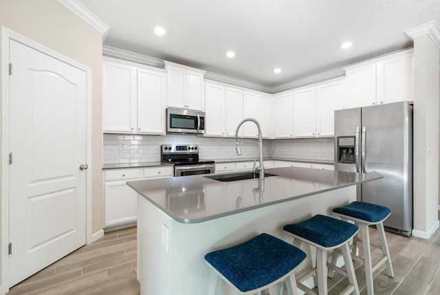 kitchen with stainless steel appliances, a kitchen bar, a sink, and wood tiled floor