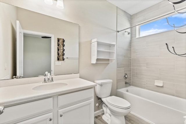 bathroom featuring toilet, wood finished floors, vanity, baseboards, and tub / shower combination