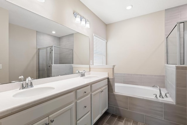 bathroom featuring a garden tub, double vanity, a stall shower, and a sink