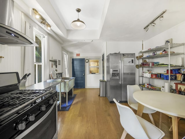 8 Davis St, Saint Augustine, FL 32084 - kitchen with stainless steel refrigerator with ice dispenser, range with gas cooktop, wall chimney exhaust hood, wood finished floors, and hanging light fixtures