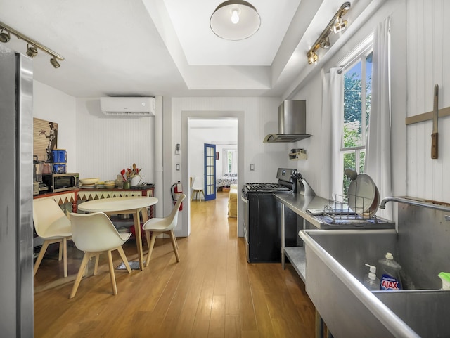 8 Davis St, Saint Augustine, FL 32084 - kitchen featuring stainless steel appliances, island range hood, a wall unit AC, wood finished floors, and a sink