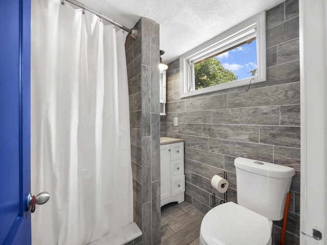 8 Davis St, Saint Augustine, FL 32084 - bathroom with tile walls, vanity, a textured ceiling, toilet, and curtained shower