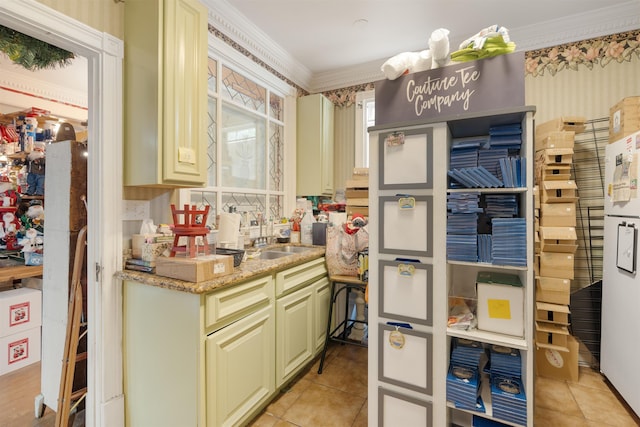 kitchen featuring sink, light stone counters, crown molding, and cream cabinets