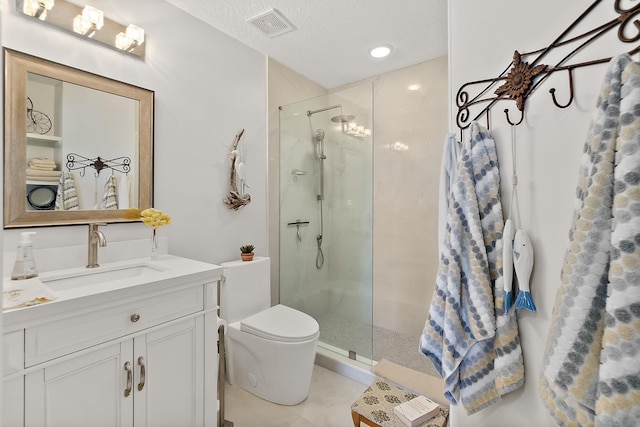 bathroom featuring vanity, tile patterned flooring, toilet, a textured ceiling, and a tile shower