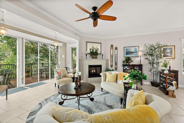 living room featuring a tile fireplace, light tile patterned floors, ceiling fan, and crown molding