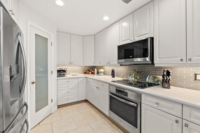 kitchen featuring white cabinets, light tile patterned flooring, stainless steel appliances, and tasteful backsplash