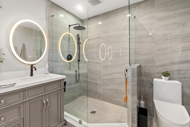 bathroom with a tile shower, vanity, and toilet