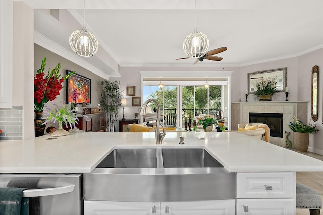 kitchen featuring backsplash, ornamental molding, ceiling fan, a tile fireplace, and white cabinetry