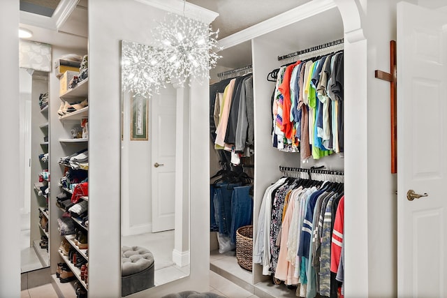 spacious closet with a chandelier and light tile patterned floors