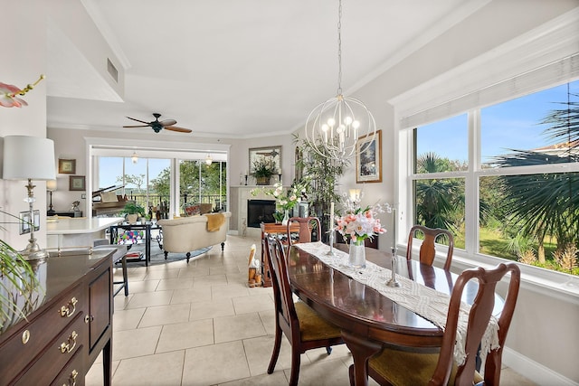 1602 Windjammer Ln, Saint Augustine, FL 32084 - dining room with crown molding, a tiled fireplace, a chandelier, light tile patterned floors, and a ceiling fan