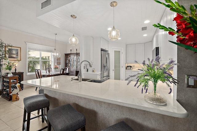 kitchen featuring sink, white cabinets, stainless steel fridge with ice dispenser, pendant lighting, and light tile patterned flooring