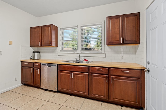 kitchen featuring baseboards, backsplash, stainless steel dishwasher, a sink, and light tile patterned flooring