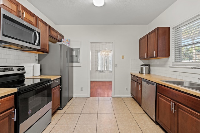 kitchen featuring light tile patterned floors, stainless steel appliances, tasteful backsplash, and a healthy amount of sunlight