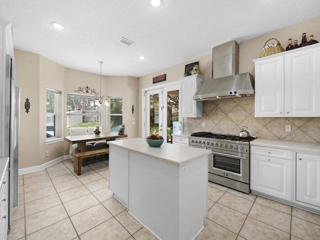 304 1st St, Saint Augustine, FL 32084 - kitchen with high end range, wall chimney exhaust hood, backsplash, a center island, and light countertops