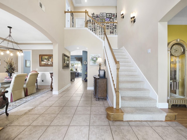 304 1st St, Saint Augustine, FL 32084 - stairway featuring arched walkways, crown molding, tile patterned floors, and a towering ceiling