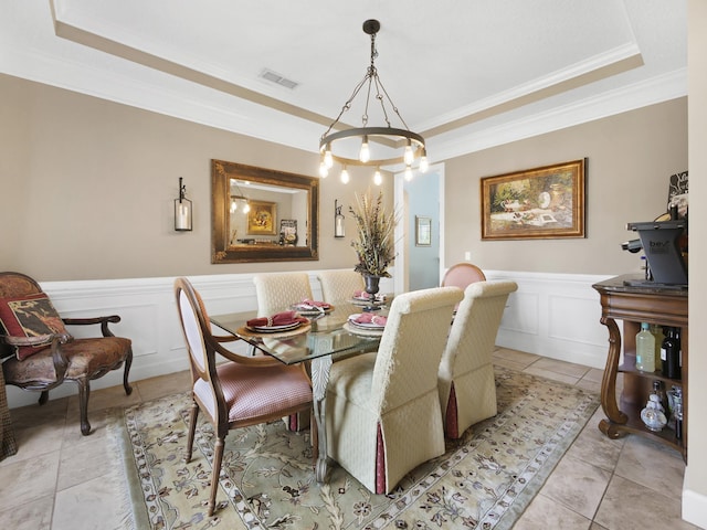 304 1st St, Saint Augustine, FL 32084 - dining area featuring a tray ceiling, crown molding, a wainscoted wall, a chandelier, and light tile patterned flooring