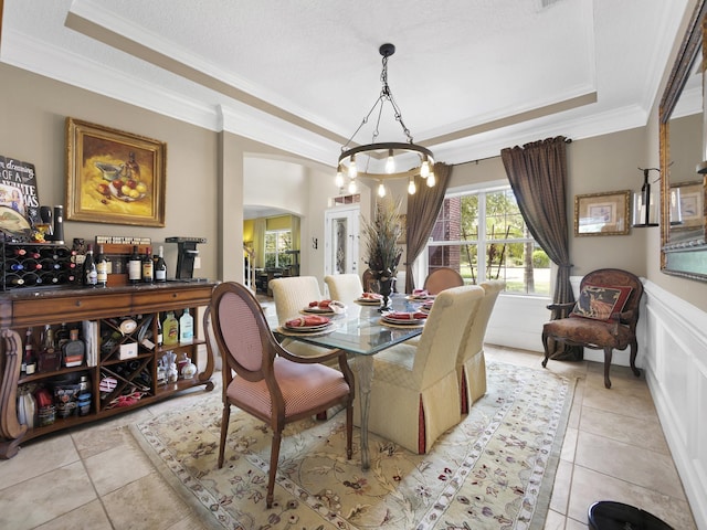304 1st St, Saint Augustine, FL 32084 - dining area with a tray ceiling, ornamental molding, arched walkways, a chandelier, and light tile patterned flooring