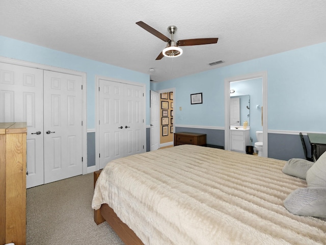 304 1st St, Saint Augustine, FL 32084 - bedroom with multiple closets, carpet, ensuite bathroom, a ceiling fan, and a textured ceiling