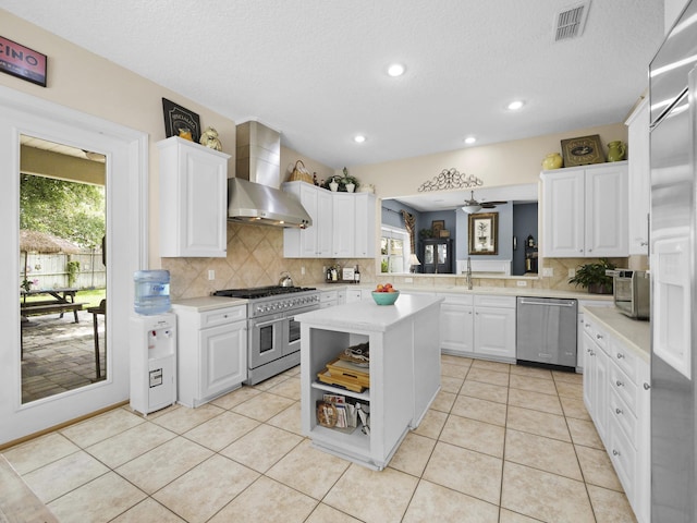 304 1st St, Saint Augustine, FL 32084 - kitchen featuring high end appliances, wall chimney range hood, light countertops, tasteful backsplash, and recessed lighting