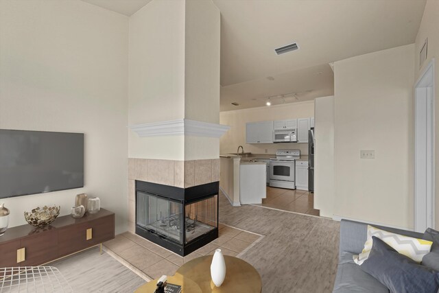 unfurnished living room featuring a tile fireplace, light wood-type flooring, and rail lighting