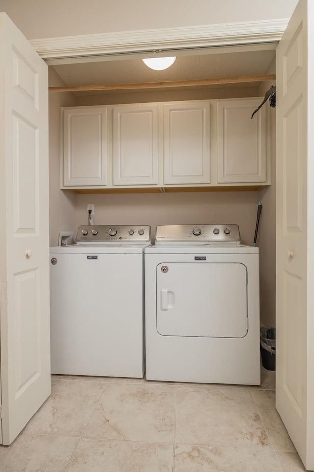 clothes washing area with light tile patterned flooring, cabinets, and washer and dryer