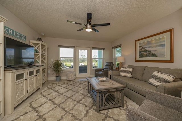 living room featuring ceiling fan and a textured ceiling