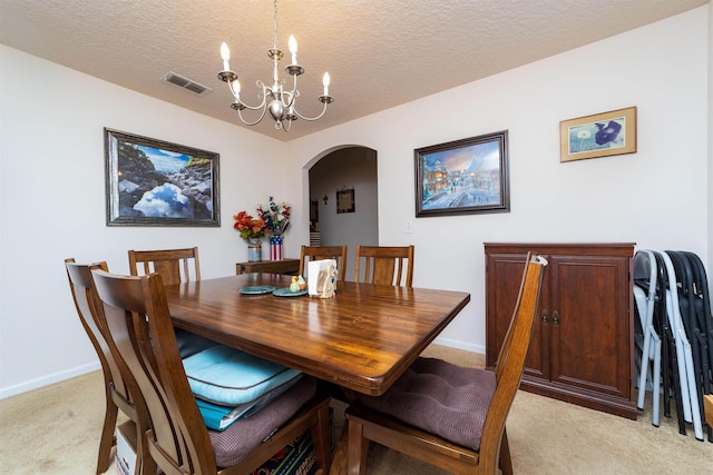 142 Patriot Ln, Elkton, FL 32033 - dining room featuring light carpet, arched walkways, a chandelier, a textured ceiling, and baseboards