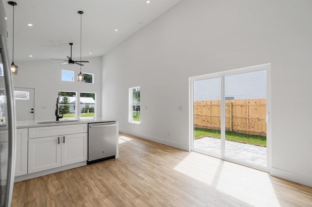 kitchen with sink, light hardwood / wood-style flooring, high vaulted ceiling, stainless steel dishwasher, and white cabinets