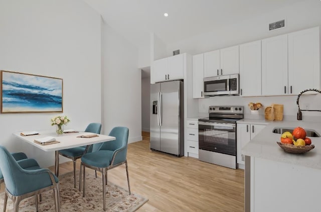 kitchen featuring white cabinets, stainless steel appliances, light hardwood / wood-style floors, and sink